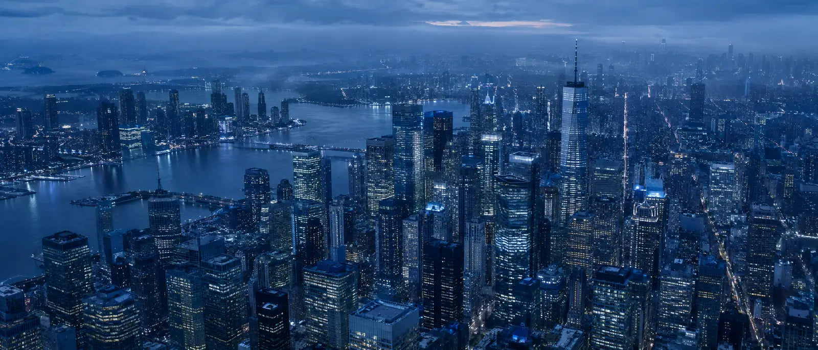 A city at blue hour seen from high above, thousands of windows lit